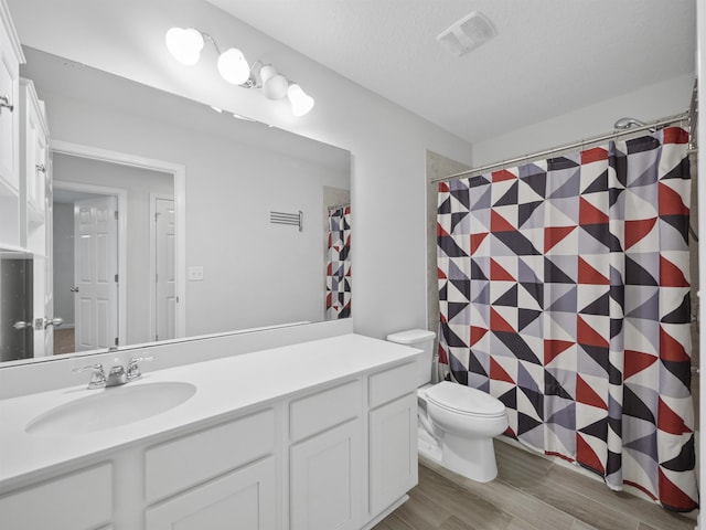 bathroom featuring vanity, toilet, wood-type flooring, and a textured ceiling