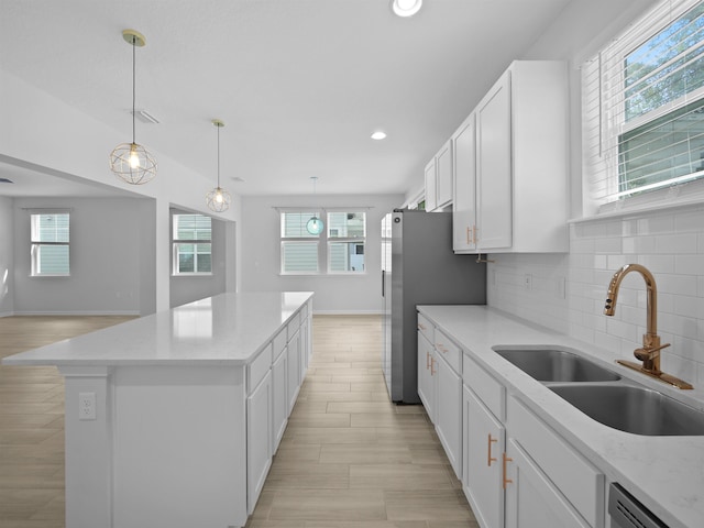 kitchen featuring white cabinets, sink, a center island, and a healthy amount of sunlight