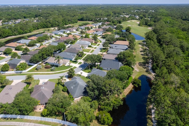 aerial view of property's location featuring a large body of water, nearby suburban area, and a forest