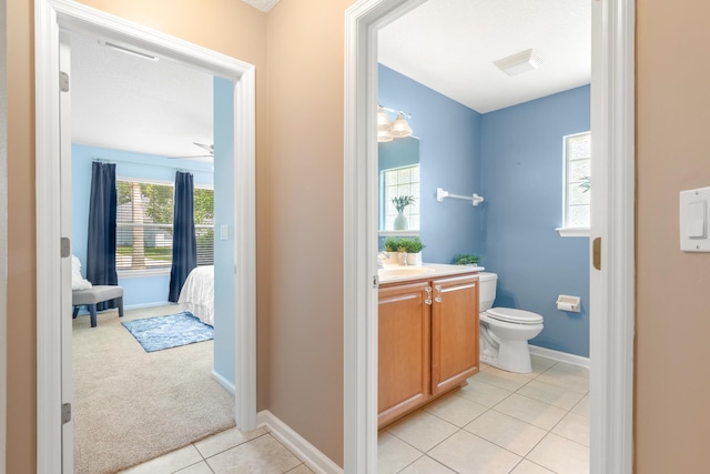 bathroom with toilet, tile patterned flooring, vanity, baseboards, and a ceiling fan