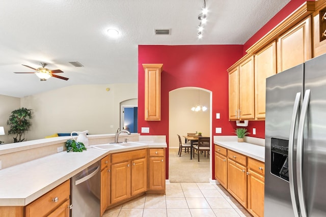 kitchen featuring stainless steel appliances, a sink, arched walkways, light countertops, and light colored carpet
