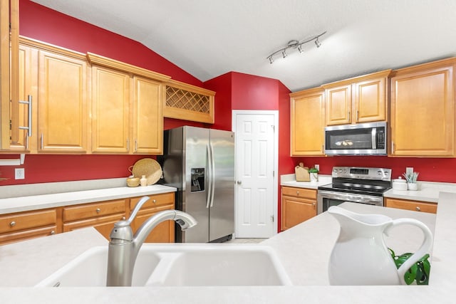 kitchen featuring stainless steel appliances, lofted ceiling, a sink, and light countertops