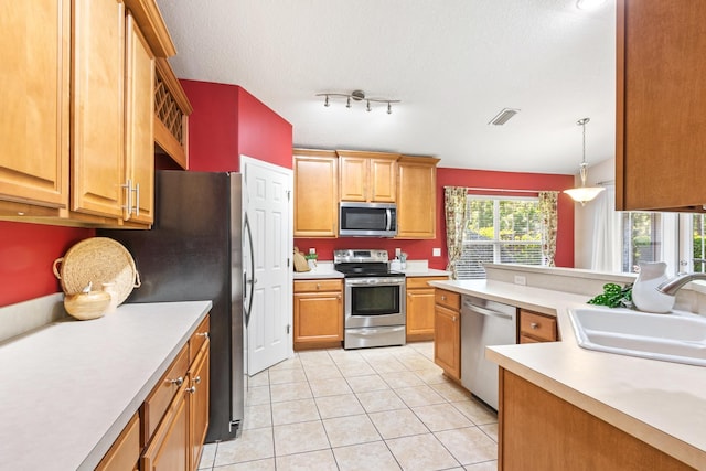 kitchen with stainless steel appliances, a sink, light countertops, light tile patterned floors, and a textured ceiling