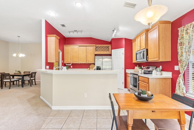 kitchen featuring stainless steel appliances, lofted ceiling, light countertops, a chandelier, and a peninsula