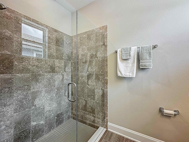 full bath with a shower stall and baseboards