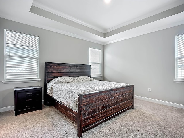 bedroom with a tray ceiling, carpet flooring, crown molding, and baseboards