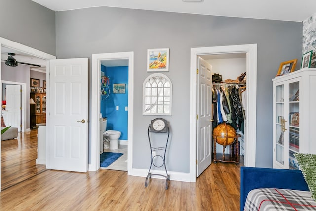 bedroom featuring a walk in closet, light hardwood / wood-style flooring, connected bathroom, a closet, and lofted ceiling