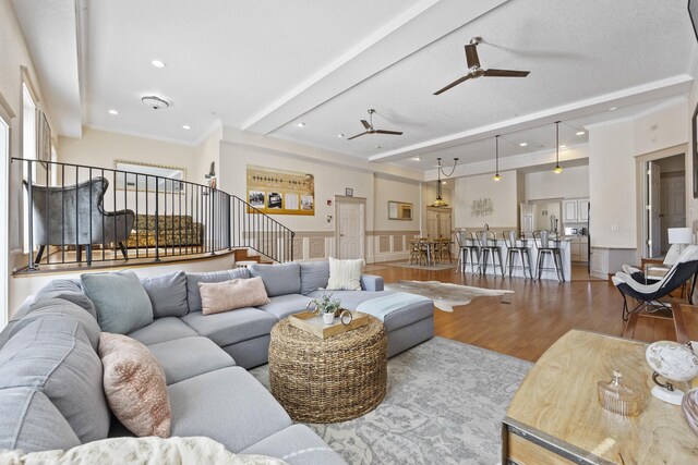 living room featuring beam ceiling, crown molding, hardwood / wood-style floors, and ceiling fan