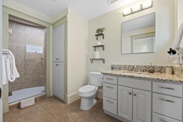 bathroom featuring an enclosed shower, vanity, a textured ceiling, tile patterned flooring, and toilet