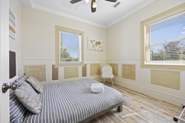 bedroom featuring multiple windows, ceiling fan, light hardwood / wood-style flooring, and ornamental molding