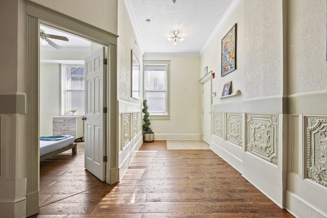 corridor with hardwood / wood-style floors, crown molding, and a textured ceiling