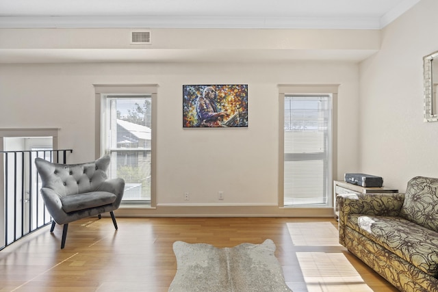 living area with light hardwood / wood-style floors and ornamental molding