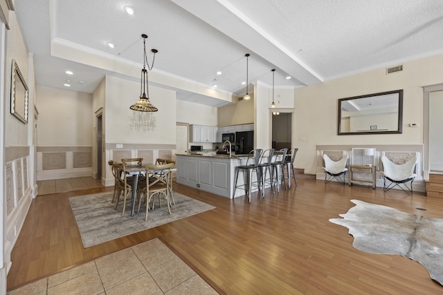 dining area featuring crown molding, sink, wood-type flooring, and a textured ceiling