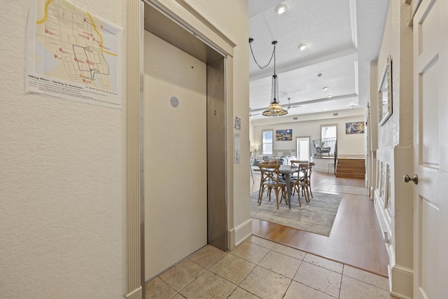 corridor with light hardwood / wood-style floors and a textured ceiling