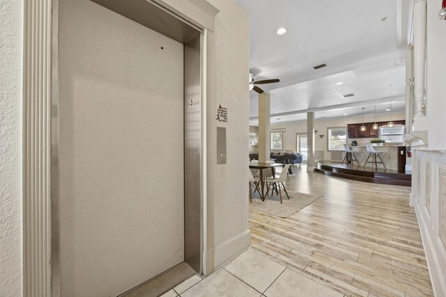 hallway featuring elevator and light hardwood / wood-style flooring