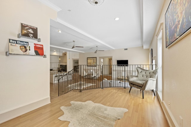 living area with hardwood / wood-style flooring, ceiling fan, and beamed ceiling