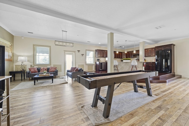 playroom featuring crown molding, light hardwood / wood-style floors, and a textured ceiling