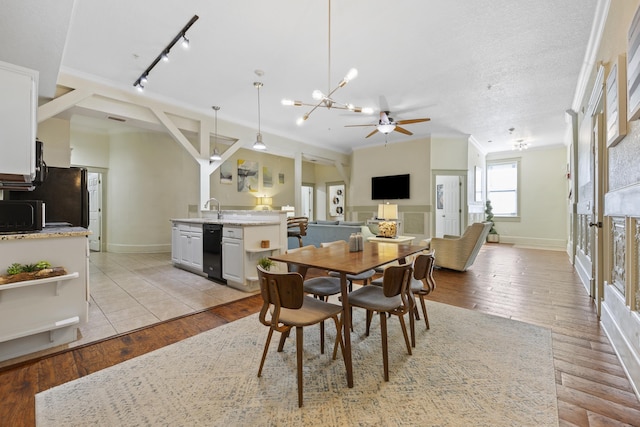 dining area featuring ceiling fan with notable chandelier, light hardwood / wood-style floors, track lighting, and sink