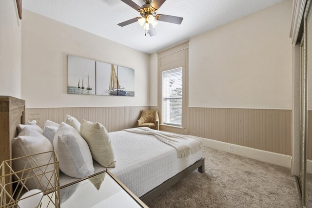 carpeted bedroom featuring ceiling fan and a textured ceiling