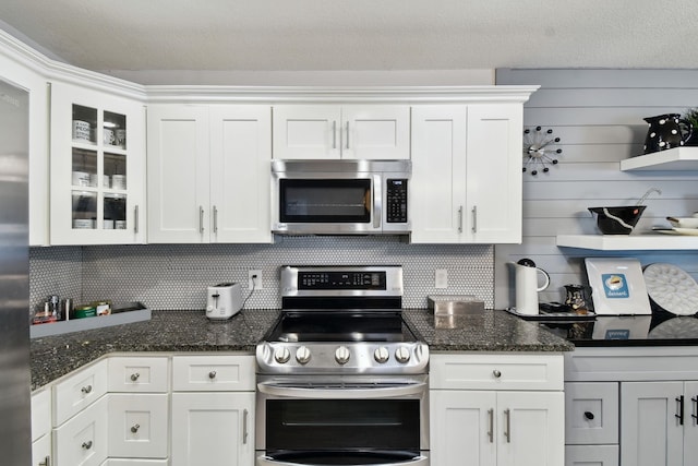 kitchen featuring sink, a breakfast bar, stainless steel appliances, a center island with sink, and dark stone counters