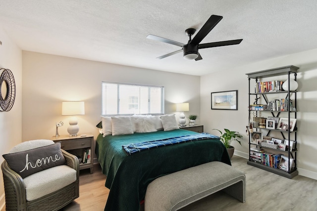 bedroom with ceiling fan, a textured ceiling, and light wood-type flooring