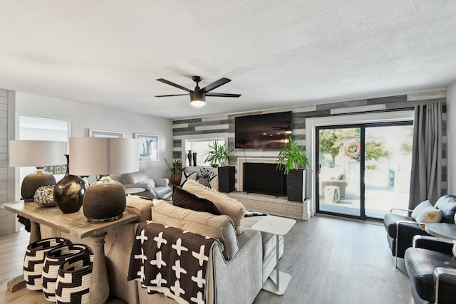 living room with a fireplace, plenty of natural light, light hardwood / wood-style floors, and a textured ceiling