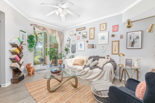 sitting room featuring ceiling fan, light wood-type flooring, a textured ceiling, and ornamental molding