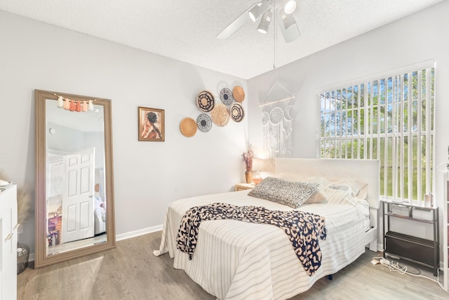 bedroom featuring ceiling fan, light wood-type flooring, and a textured ceiling