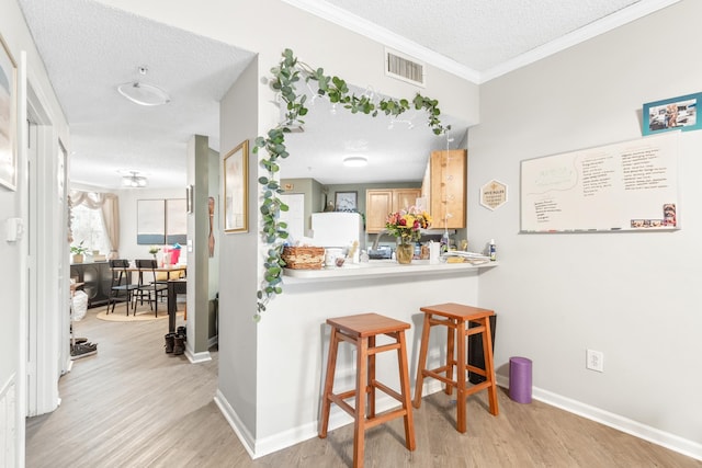 kitchen featuring light brown cabinets, light wood-type flooring, and a textured ceiling