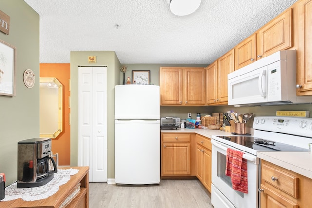 kitchen featuring light wood-type flooring, white appliances, and a textured ceiling