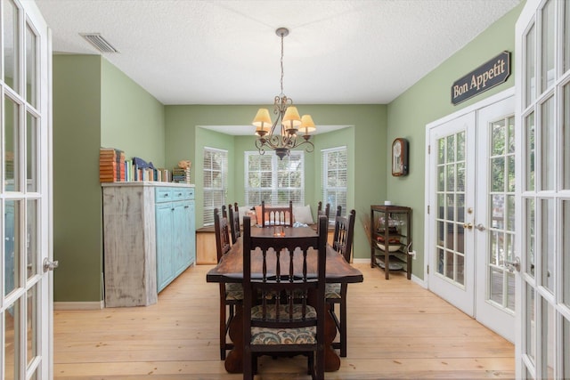 1440 Corunna St, Saint Augustine, FL 32080 - dining area featuring visible vents, french doors, an inviting chandelier, light wood-style floors, and a textured ceiling