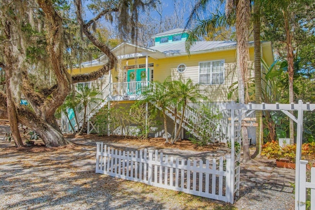 1440 Corunna St, Saint Augustine, FL 32080 - view of front of house featuring metal roof, covered porch, a fenced front yard, and stairs