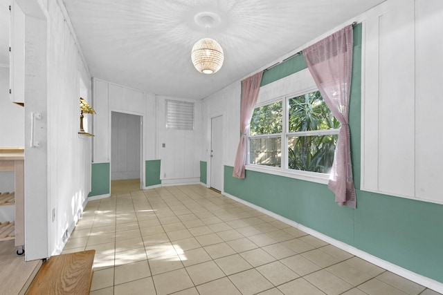 empty room featuring baseboards and light tile patterned floors