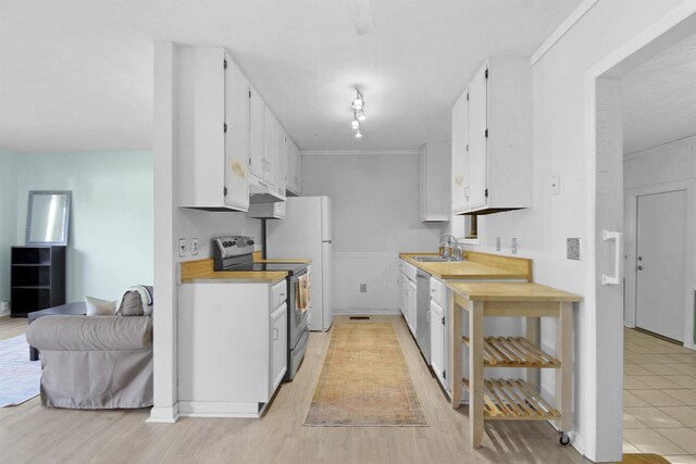 kitchen with appliances with stainless steel finishes, white cabinets, light countertops, a sink, and under cabinet range hood