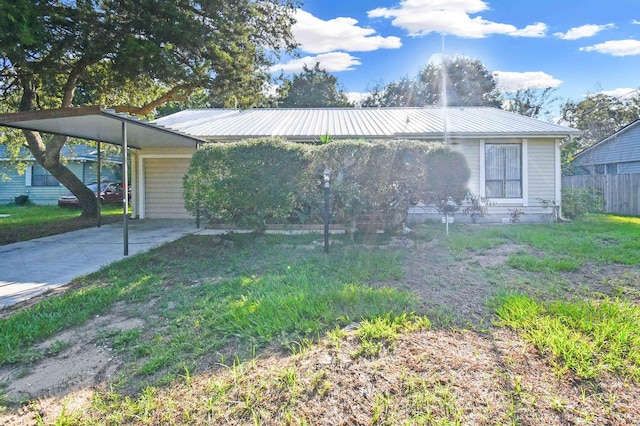 ranch-style home featuring a carport, metal roof, concrete driveway, and fence