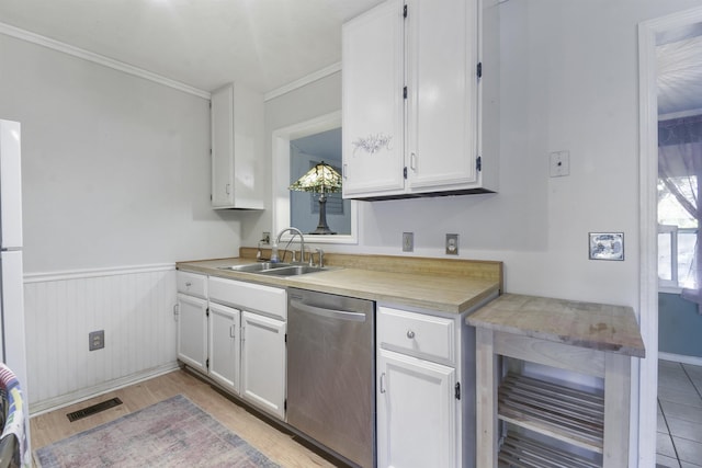 kitchen with a sink, stainless steel dishwasher, white cabinets, ornamental molding, and light countertops