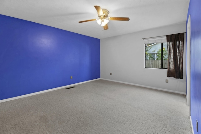 spare room with carpet floors, a ceiling fan, and baseboards