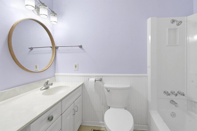 bathroom with a wainscoted wall, vanity, toilet, and  shower combination