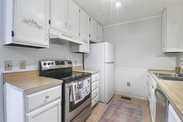 kitchen with appliances with stainless steel finishes, under cabinet range hood, a sink, light wood finished floors, and white cabinets