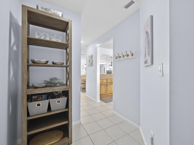 corridor featuring light tile patterned floors and a textured ceiling