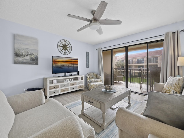 living room featuring hardwood / wood-style flooring, ceiling fan, and a textured ceiling