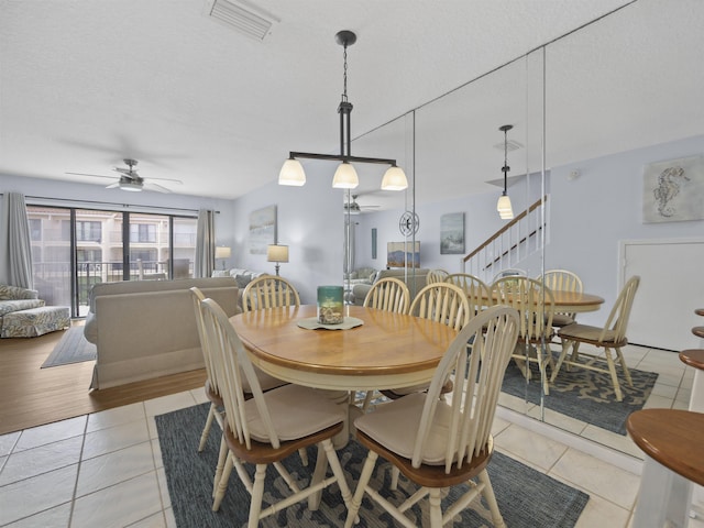 tiled dining room with a textured ceiling and ceiling fan