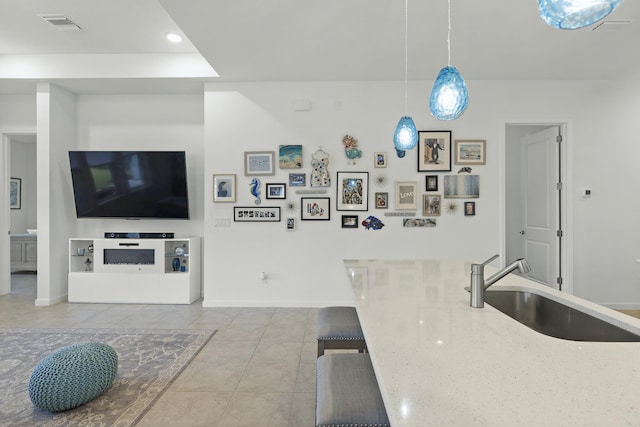 kitchen featuring pendant lighting, light tile patterned flooring, light stone counters, and sink