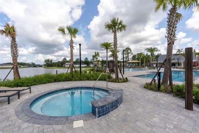 view of swimming pool with a water view and a hot tub