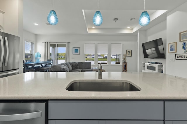 kitchen with pendant lighting, light stone counters, and sink