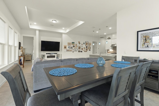 tiled dining space with a raised ceiling