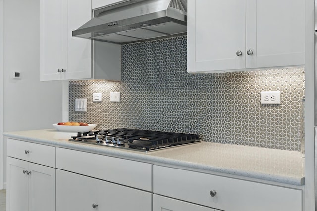 kitchen featuring decorative backsplash, white cabinetry, and extractor fan