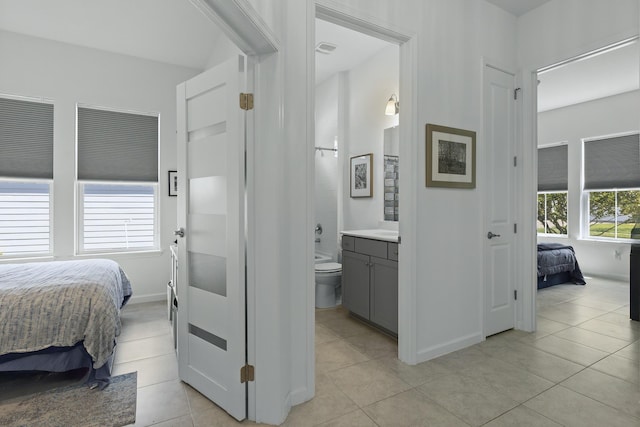 bedroom featuring light tile patterned floors, ensuite bathroom, and multiple windows