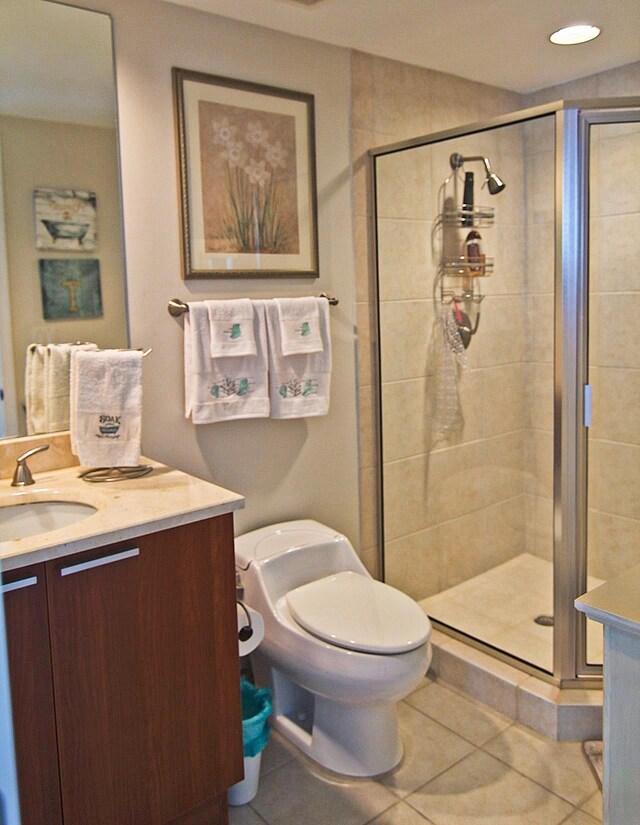 bathroom with tile patterned flooring, vanity, toilet, and an enclosed shower