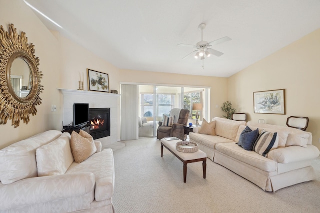living room with vaulted ceiling, a fireplace with flush hearth, carpet floors, and ceiling fan